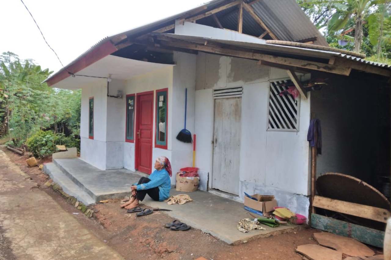 Seorang penduduk miskin penerima program PKH duduk di depan rumahnya