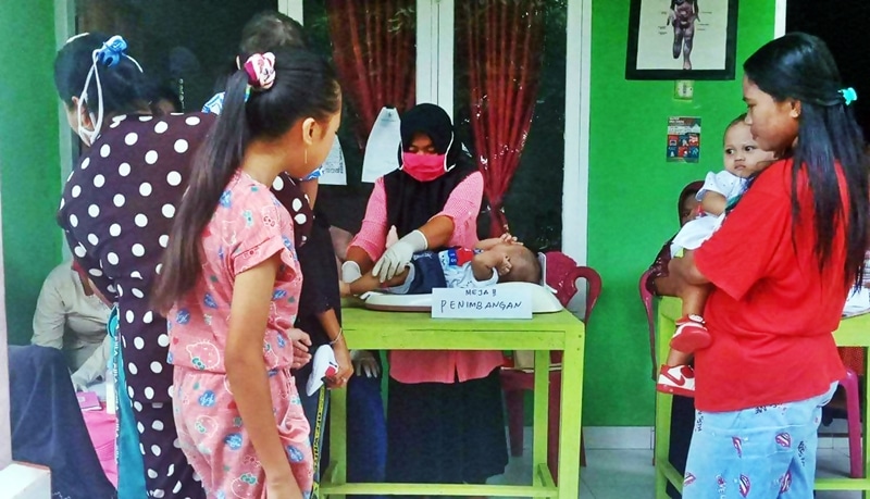 beberapa orang wanita bersama anak-anaknya memeriksa kondisi kesehatannya di Posyandu