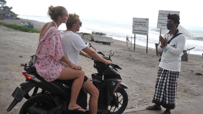 Turis asing di Bali menaiki motor di pasir pantai